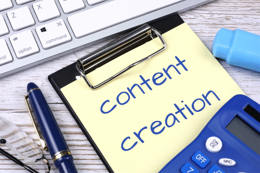 A notepad with "content creation" written on it sits on a desk with a keyboard and calculator, illustrating how AI tools for social media marketing can assist in generating content.